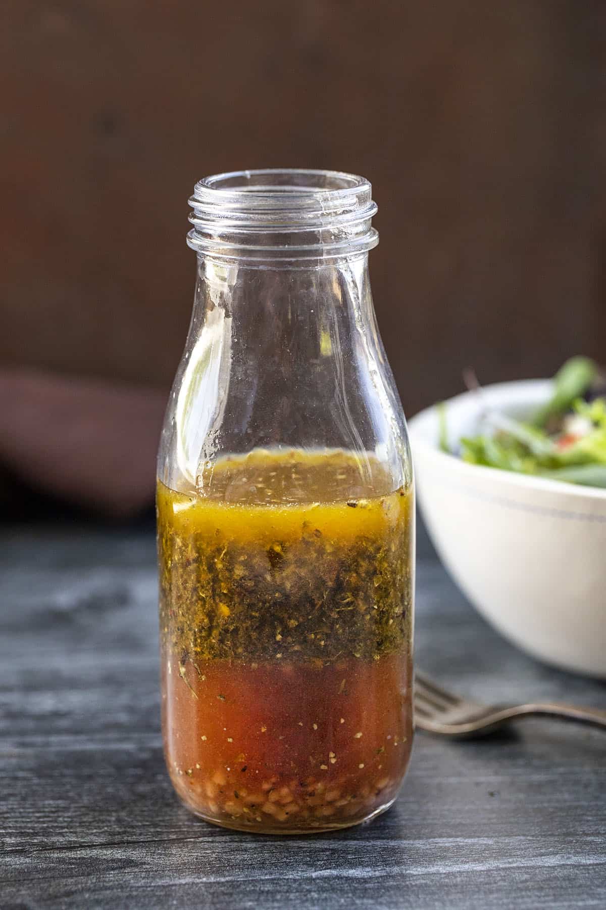 Bottle of Italian Dressing on Counter with Salad Bowl Behind It