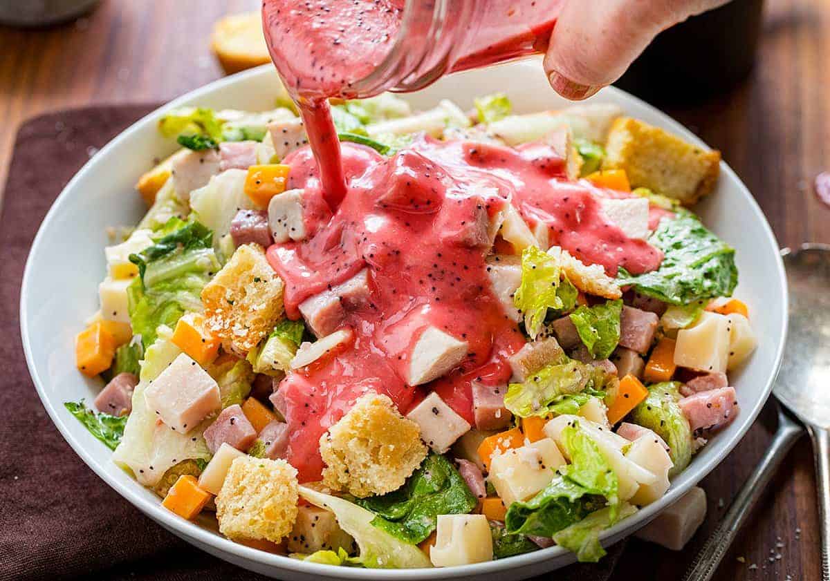Pouring Raspberry Poppyseed Dressing Over a Monte Cristo Salad. 