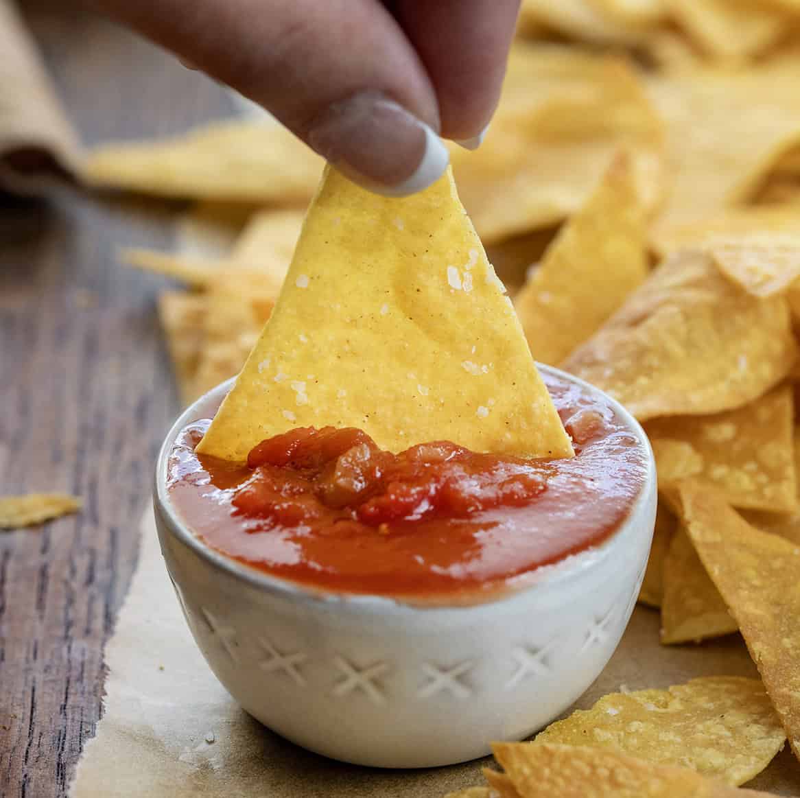 Dipping homemade Tortilla Chips into salsa.