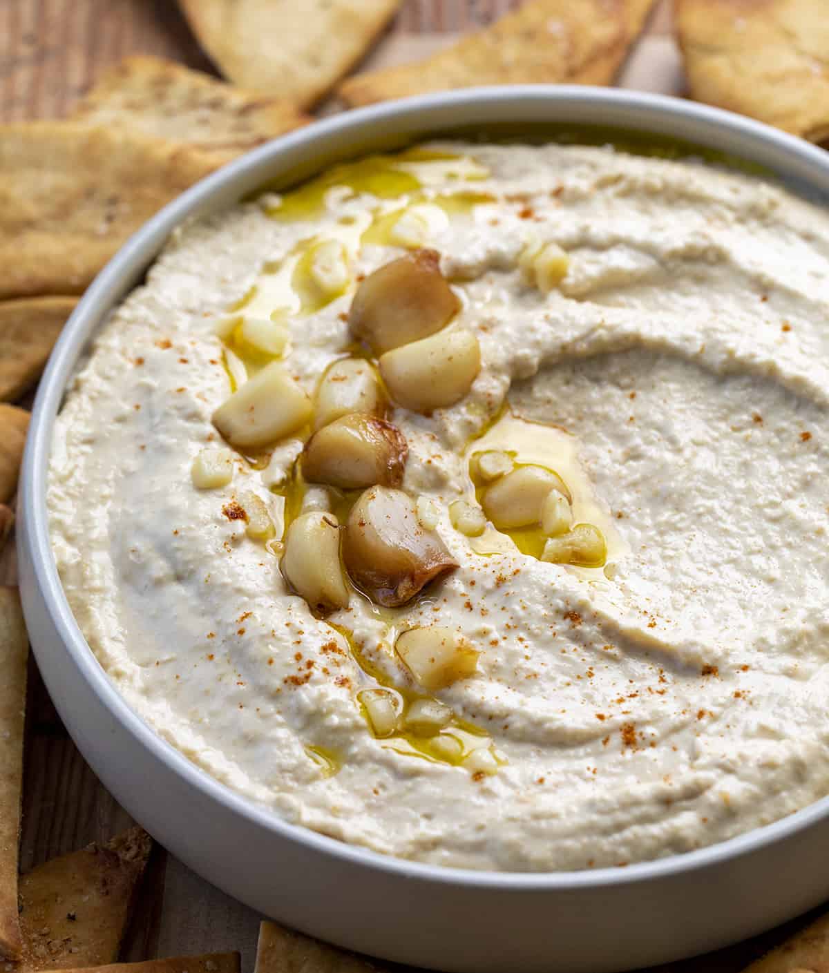 Bowl of Roasted Garlic Hummus with Roasted Garlic Cloves on Top. Hummus, Hummus Recipes, How to Make Creamy Hummus, Ice Cubes in Hummus, Appetizer, What to Eat with Hummus, recipes, i am homesteader, iamhomesteader