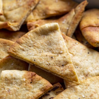 Crispy Pita Chips on a Cutting Board Next to Hummus. Pita Chips, How to Make Pita Chips, Air Fryer Pita Chips, Pita Chips in the Oven, Seasoned Pita Chips, Crispy Pita Chips, recipes, Appetizers, i am homesteader, iamhomesteader