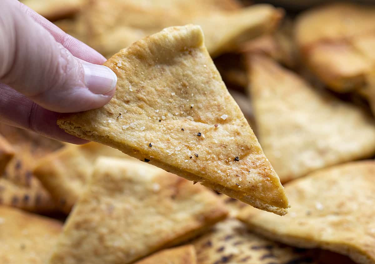 Hand Holding Homemade Crispy Pita Chip. Pita Chips, How to Make Pita Chips, Air Fryer Pita Chips, Pita Chips in the Oven, Seasoned Pita Chips, Crispy Pita Chips, recipes, Appetizers, i am homesteader, iamhomesteader