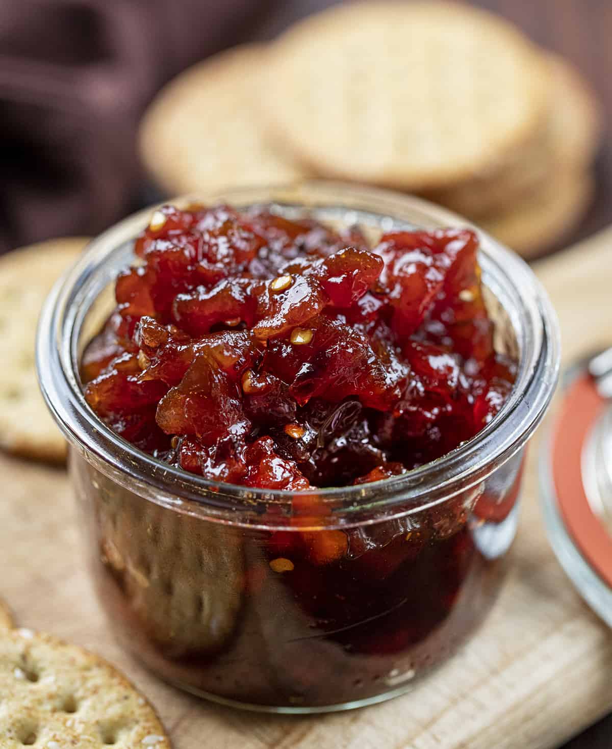 Jar of Spicy Tomato Jam on a Cutting Board. Appetizer, Burger Topping Idea, Tomato Jam, How to Make Tomato Jam, Spicy Jam, Homemade Tomato Jam, How to Can Tomato Jam, Cracker Spreads, Super Bowl Food, Christmas Appetizers, Thanksgiving Appetizers, i am homesteader, iamhomesteader
