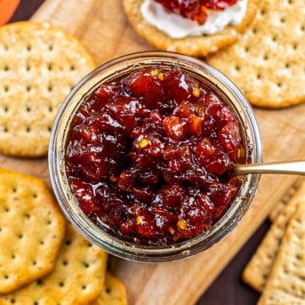 Jar of Spicy Tomato Jam with Crackers on a Cutting Board. Appetizer, Burger Topping Idea, Tomato Jam, How to Make Tomato Jam, Spicy Jam, Homemade Tomato Jam, How to Can Tomato Jam, Cracker Spreads, Super Bowl Food, Christmas Appetizers, Thanksgiving Appetizers, i am homesteader, iamhomesteader