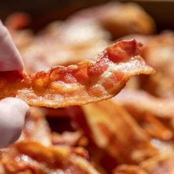 Hand Holding Piece of Crispy Bacon Made in an Air Fryer. Side Dish, How to Make Bacon, Crispy Bacon, Air Fryer Recipes, Breakfast, Breakfast bacon, Easy Bacon, Quick Bacon, i am homesteader, iamhomesteader