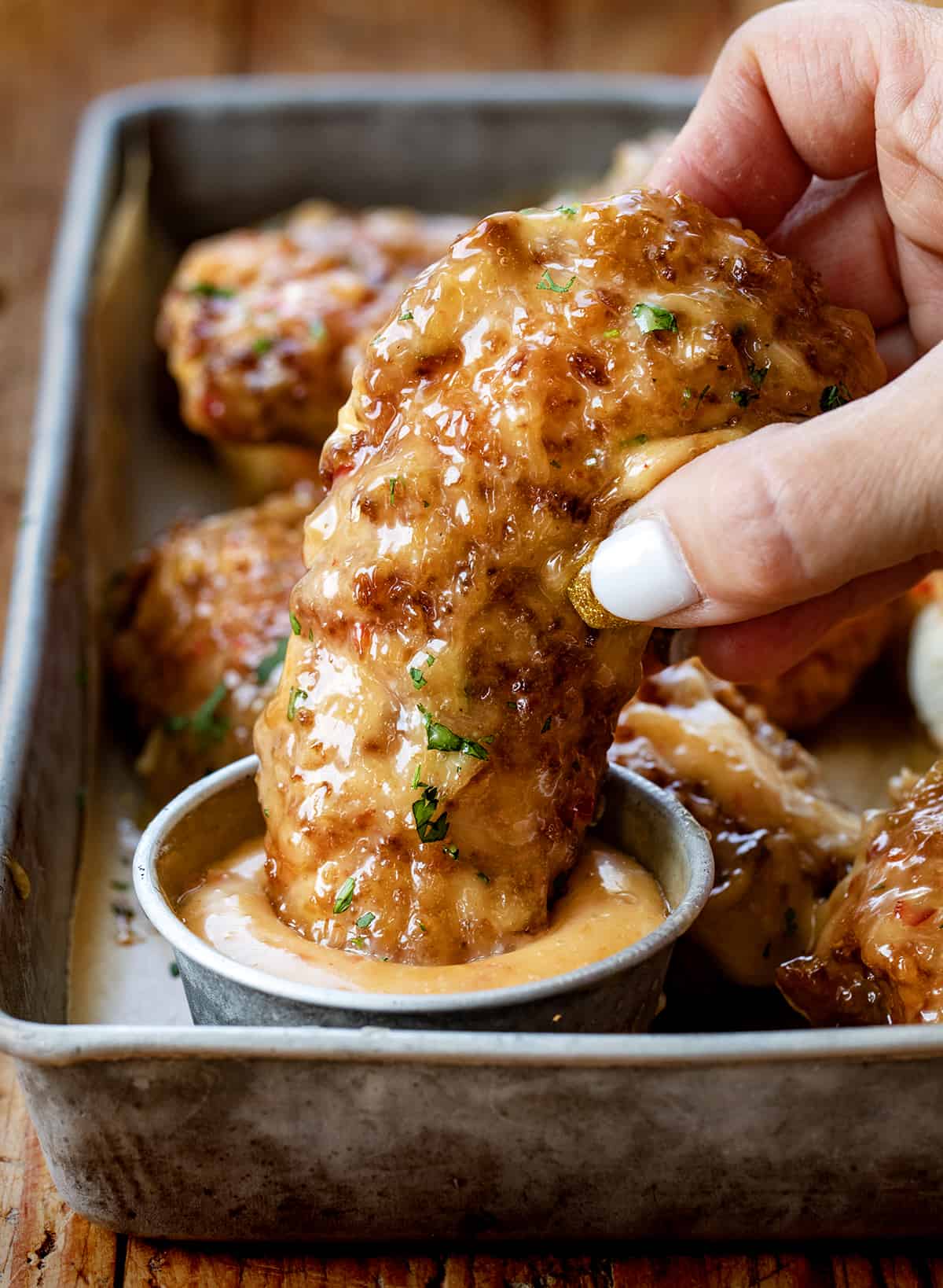 Hand Dipping a Bang Bang Chicken Tender into Bang Bang Sauce.