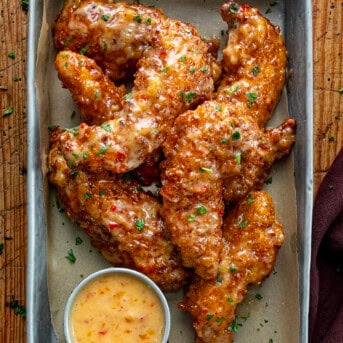 Crispy Bang Bang Chicken Tenders in a Pan with Sauce on a Wooden Table.