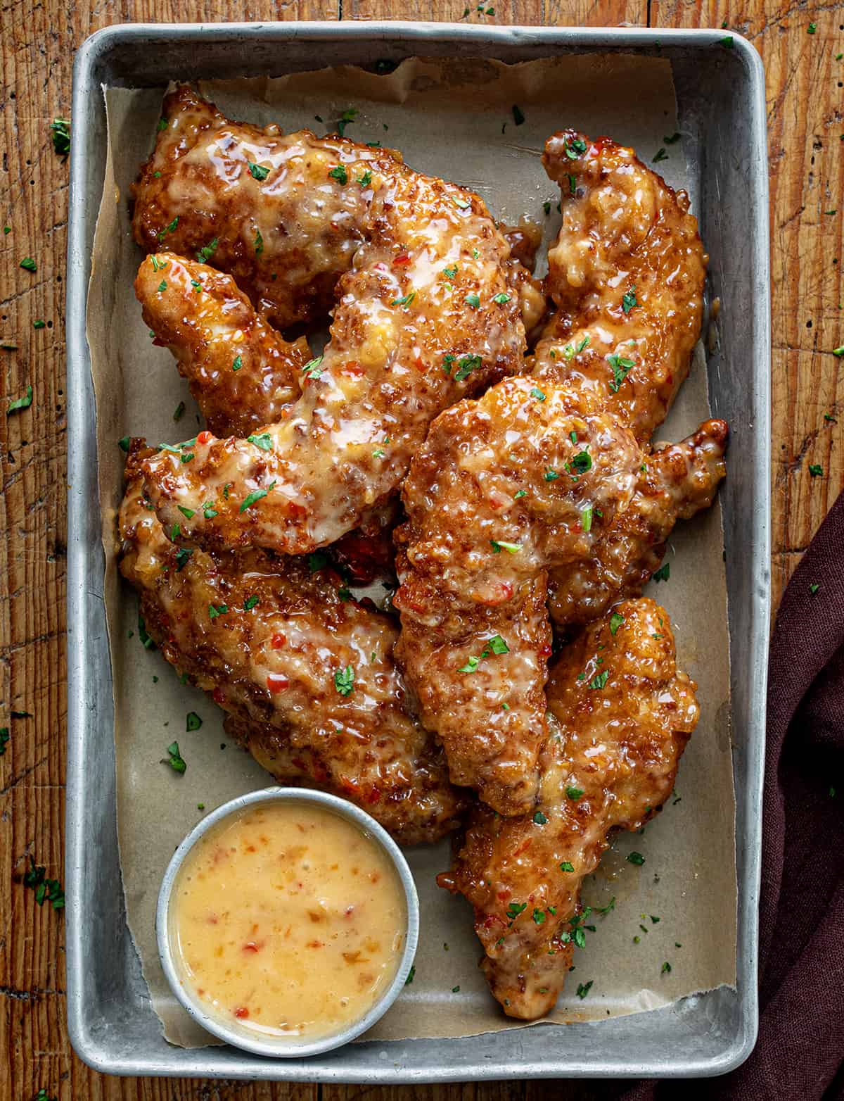 Crispy Bang Bang Chicken Tenders in a Pan with Sauce on a Wooden Table.