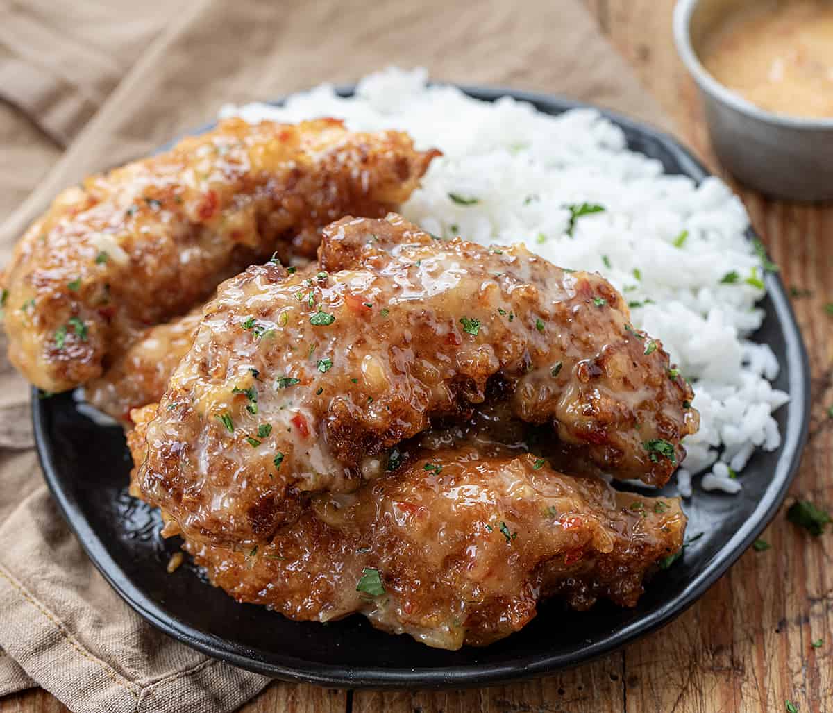 Plated Bang Bang Chicken that is Crispy on a Bed of Rice on a Wooden Table.