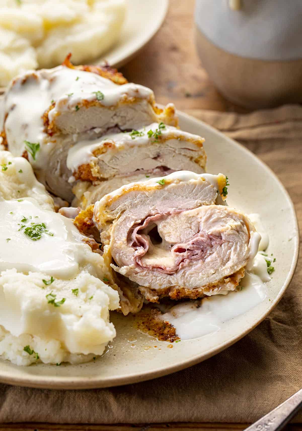 Sliced Chicken Cordon Bleu on a Plate with Mashed Potatoes and Swiss Cheese Sauce. Dinner, Supper, Air Fryer Recipes, Chicken, Chicken Recipes, Chicken Cordon Bleu, Air Fryer Chicken Cordon Bleu, Swiss Cheese Sauce, How to Make Cheesy Sauce with Swiss Cheese, i am homesteader, iamhomesteader