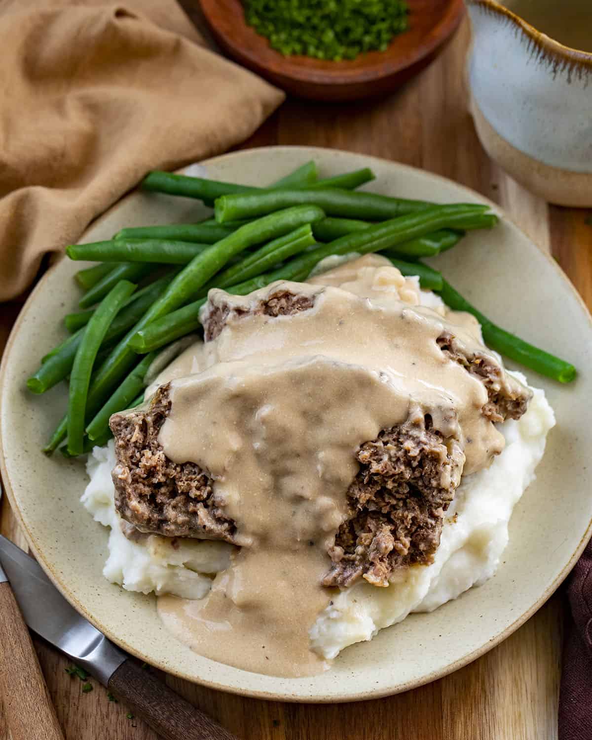 Plates of Mashed Potatoes Green Beans and Swedish Meatloaf.