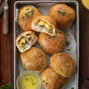Pan of Breakfast Bombs with Melted Butter and Halved Breakfast Bomb Showing Inside. Breakfast, Easy Breakfast, Kid Breakfast, Breakfast Ideas, Sausage and Egg Breakfast, Sausage Egg Cheese Breakfast, Hot Breakfast, Brunch, Brunch IDeas, brunch recipes, i am homesteader, iamhomesteader