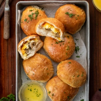 Pan of Breakfast Bombs with Melted Butter and Halved Breakfast Bomb Showing Inside. Breakfast, Easy Breakfast, Kid Breakfast, Breakfast Ideas, Sausage and Egg Breakfast, Sausage Egg Cheese Breakfast, Hot Breakfast, Brunch, Brunch IDeas, brunch recipes, i am homesteader, iamhomesteader