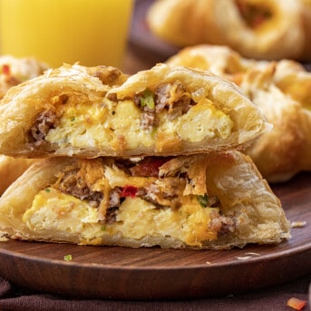 A Cowboy inspired Breakfast Puff Pastry Cut in Half on a Plate Showing Eggs, cheese, and Sausage Mixture Inside.