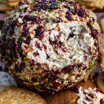 Cranberry Pecan Cheese Ball with Some Removed and Some on a Cracker in Front.