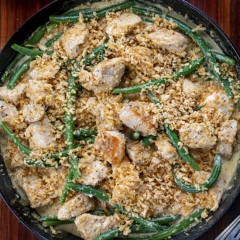Crispy Chicken Bites in a Skillet with Frenches Fried Onions Crumbled on Top with Green Beans.