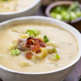 Bowl of Potato Soup with Garnish Next to Another Full Bowl.