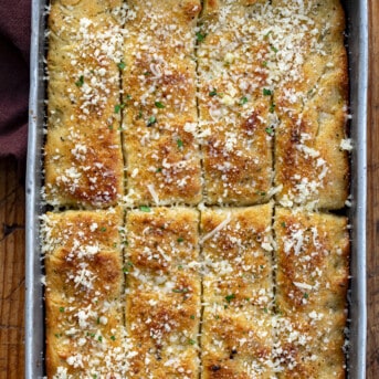 Focaccia Breadsticks in a Pan Cut up and Sprinkled with Parmesan.