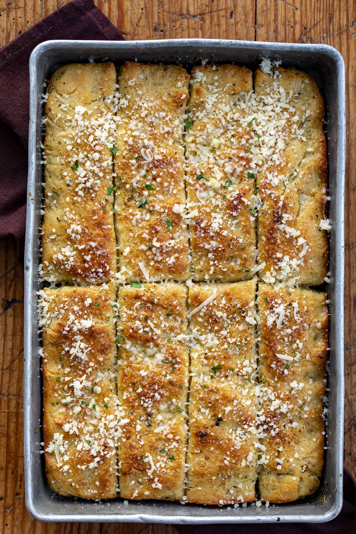 Focaccia Breadsticks in a Pan Cut up and Sprinkled with Parmesan.