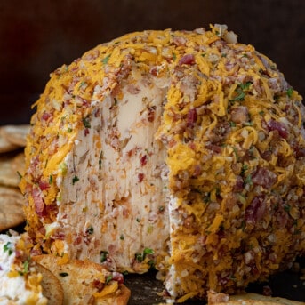 A Classic Cheese Ball that has Been Cut Into Showing the Inside and Surrounded by Crackers.