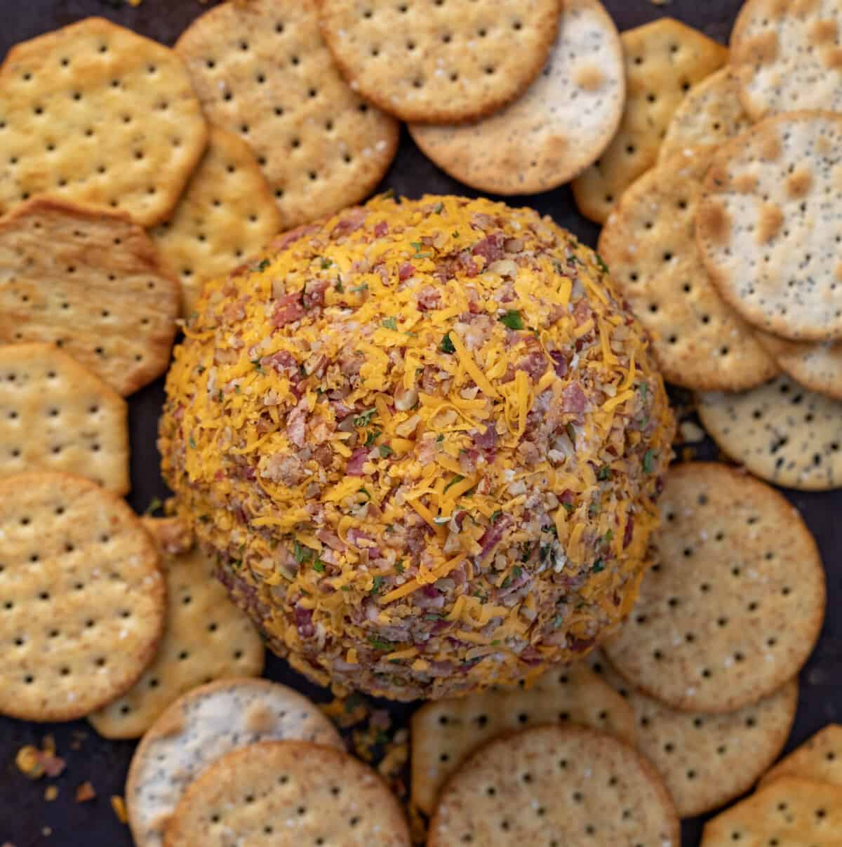 A Classic Cheeseball from Overhead on a Cutting Board Surrounded by Crackers.