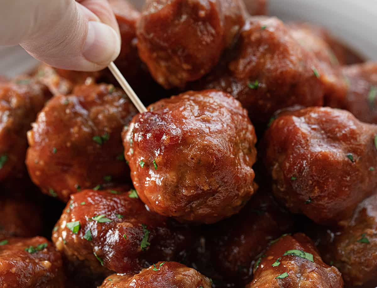 Hand Holding a Toothpick with a Slow Cooker Cranberry Meatball on It.