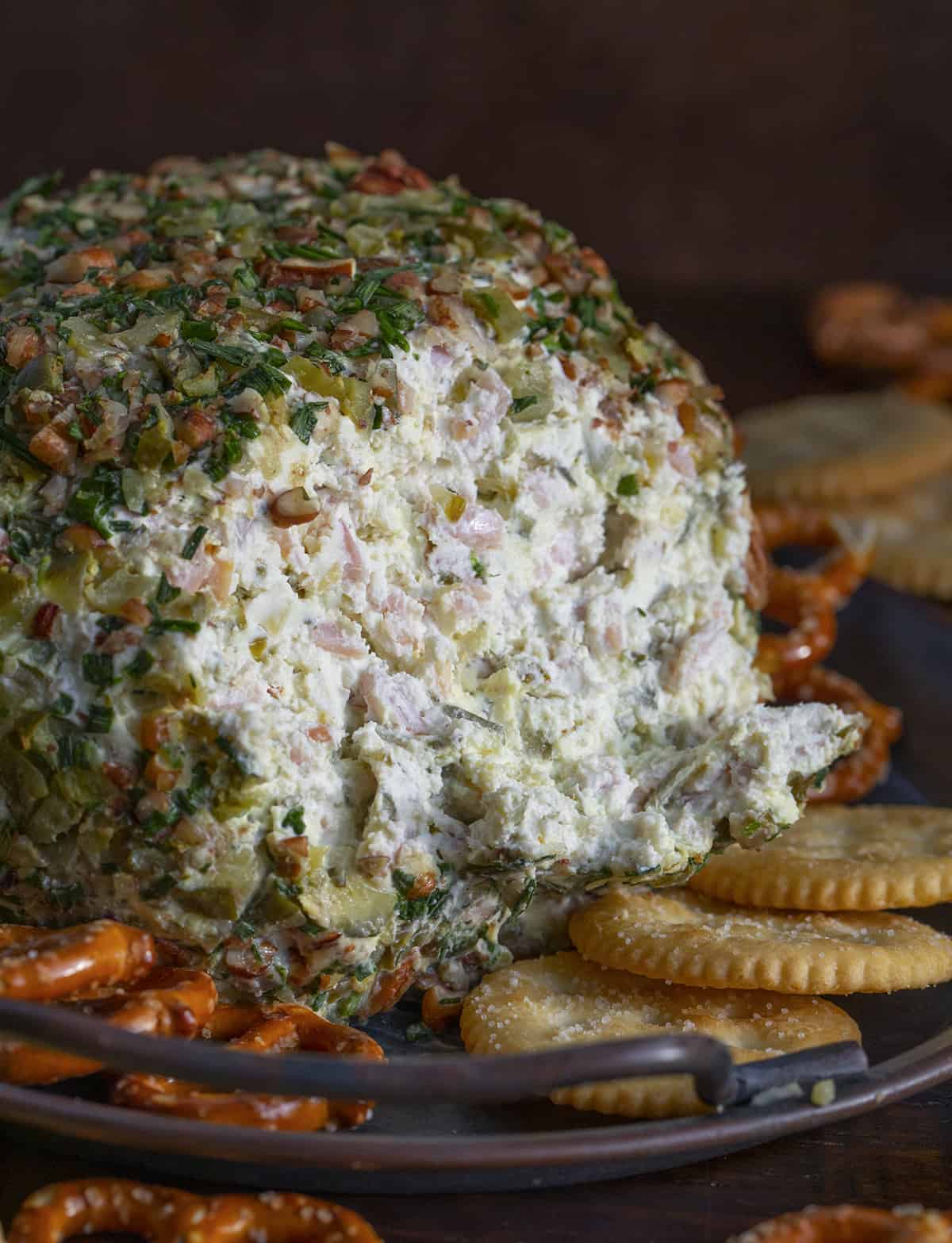 Cut Into Dill Pickle Cheese Ball Surrounded by Crackers on a Serving Platter.