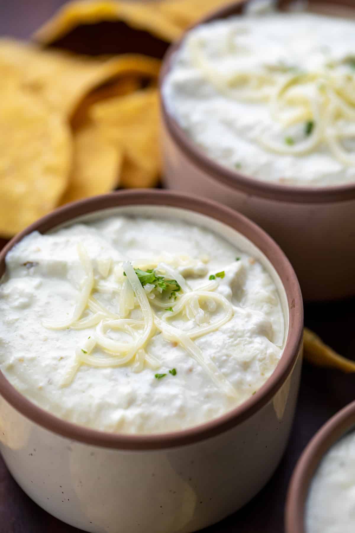 Mini Bowls of Easy Queso with Shredded Cheese and Surrounded by Chips.