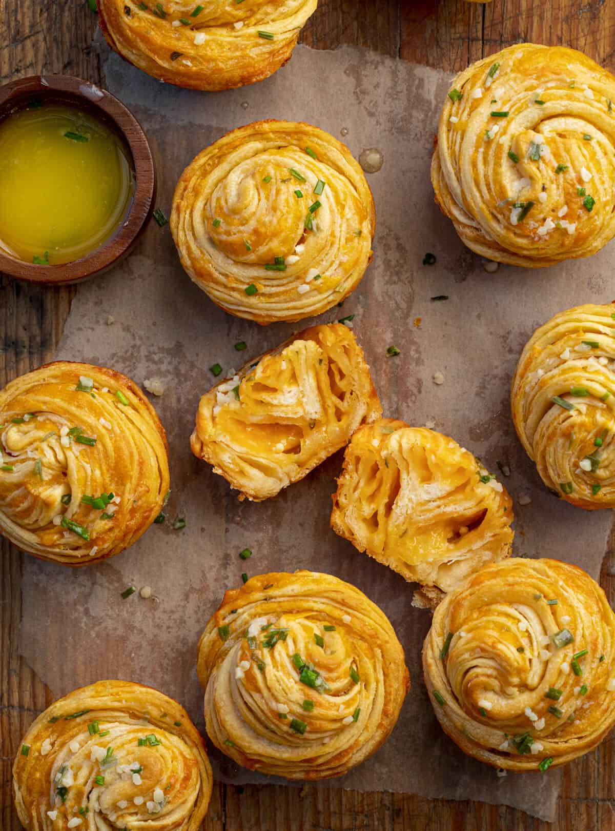 Cheesy Garlic Cruffins on parchment paper and next to melted butter from overhead.