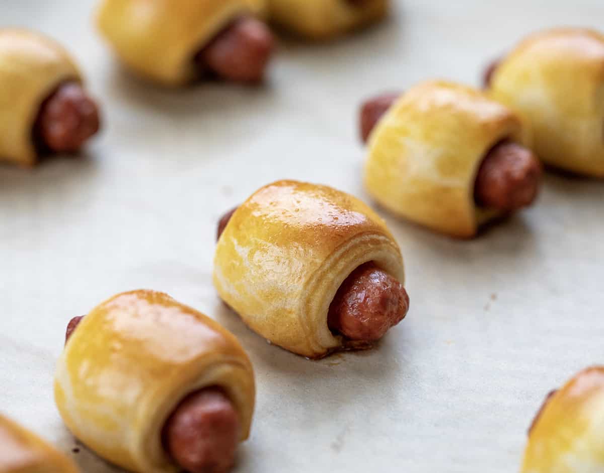 Freshly baked pigs in a blanket on a baking pan.