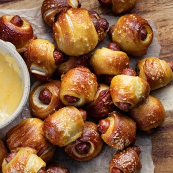 Pretzel Pigs in a Blanket on a Cutting Board with a Cheese Bowl.