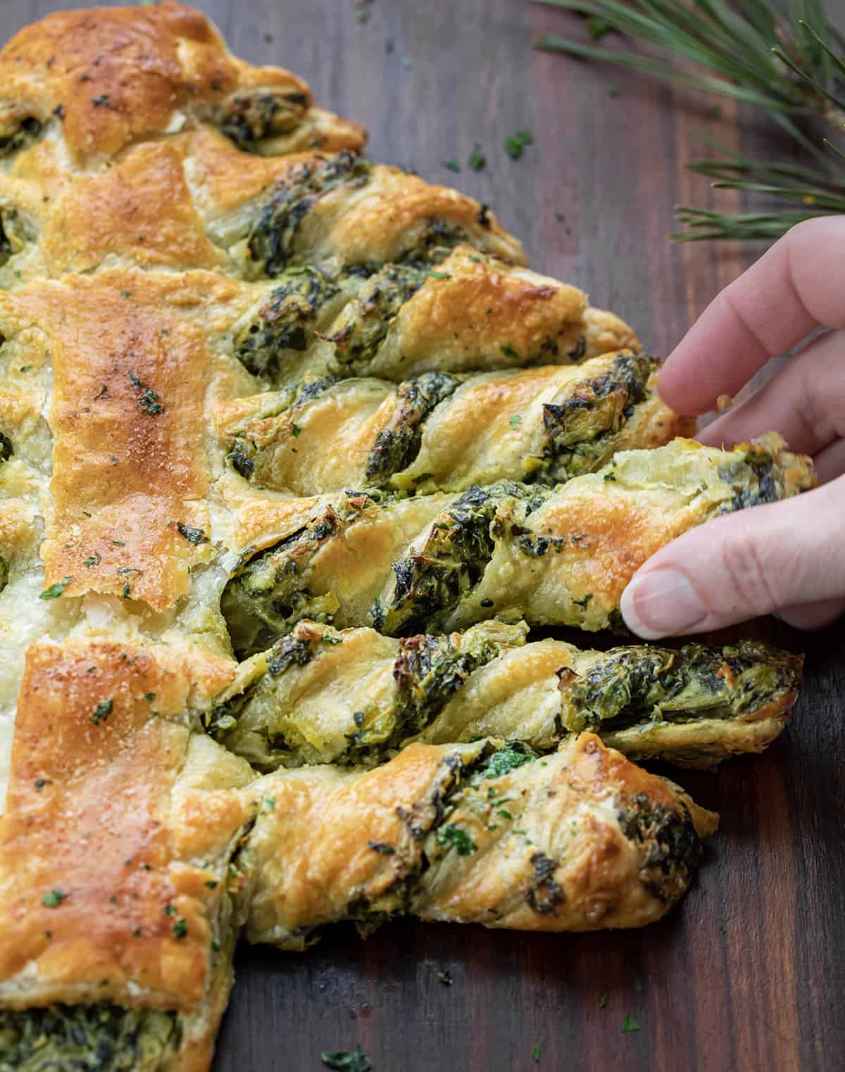 Hand Picking up a Piece of Spinach Dip Pull-Apart Christmas Tree