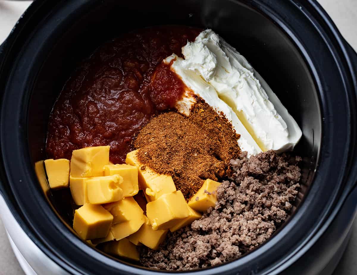 Ingredients for Slow Cooker Taco Dip inside a Slow Cooker.