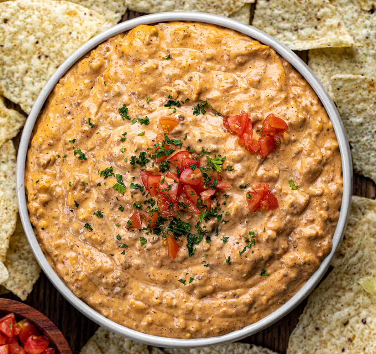Bowl of Slow Cooker Taco Dip on a Cutting Board Surrounded by Tortilla Chips.