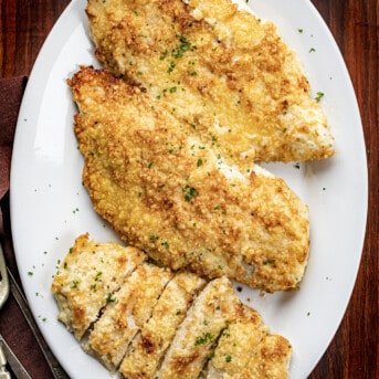Platter of Mayonnaise Parmesan Chicken on a Cutting Board with Silverware.