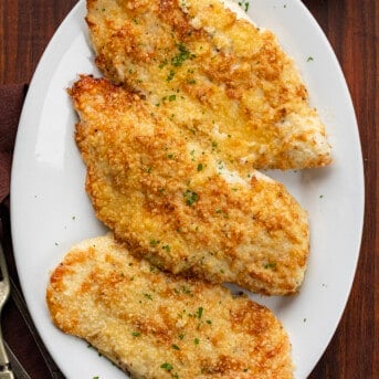 Platter of Mayonnaise Parmesan Chicken on a Cutting Board with Silverware.