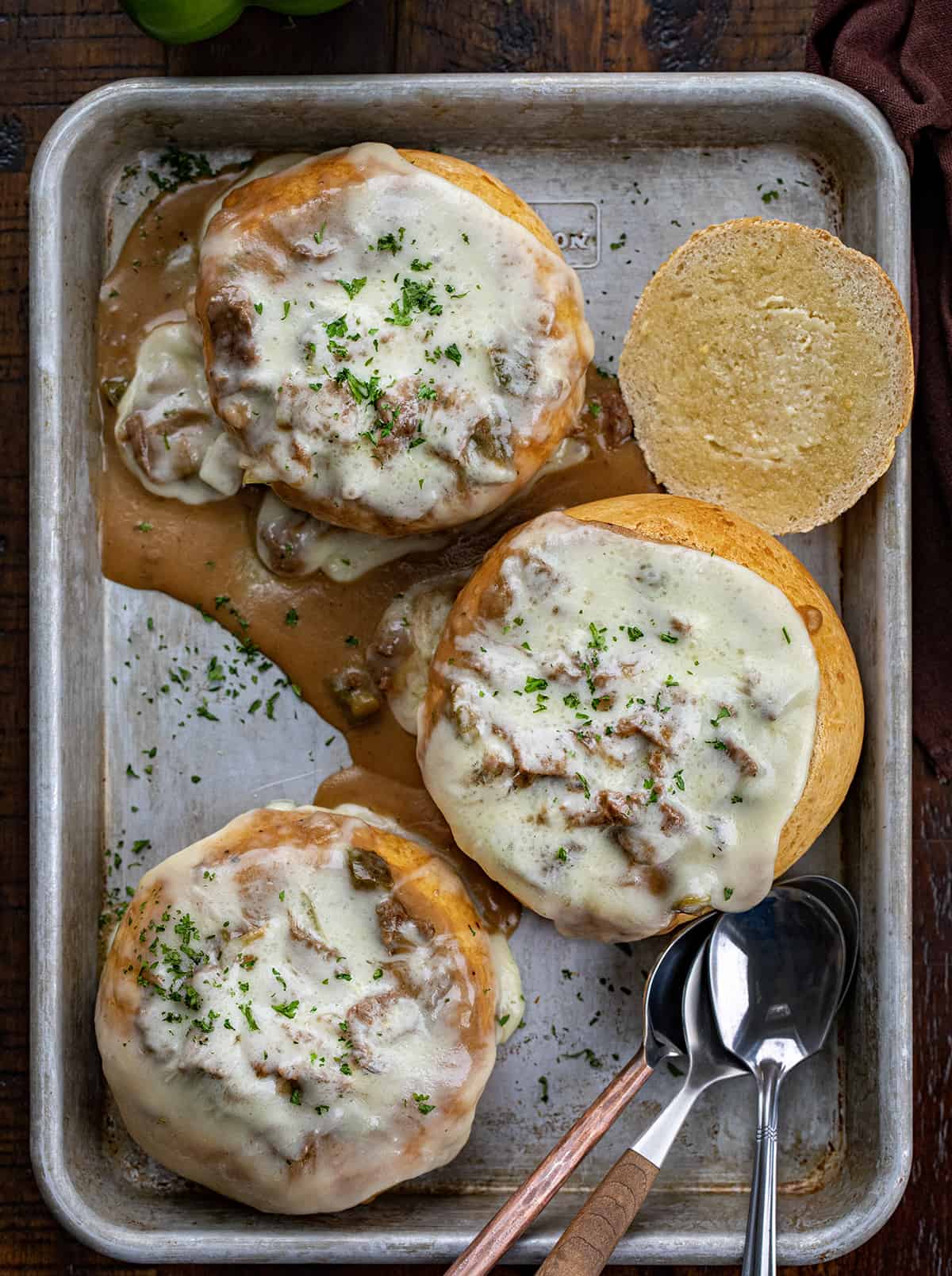 Breadbowls Filled with Philly Cheesesteak Stew and Covered in Cheese