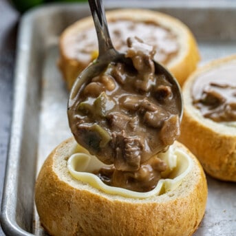 Spooning Philly Cheesesteak Stew into a Breadbowl Lined with Cheese