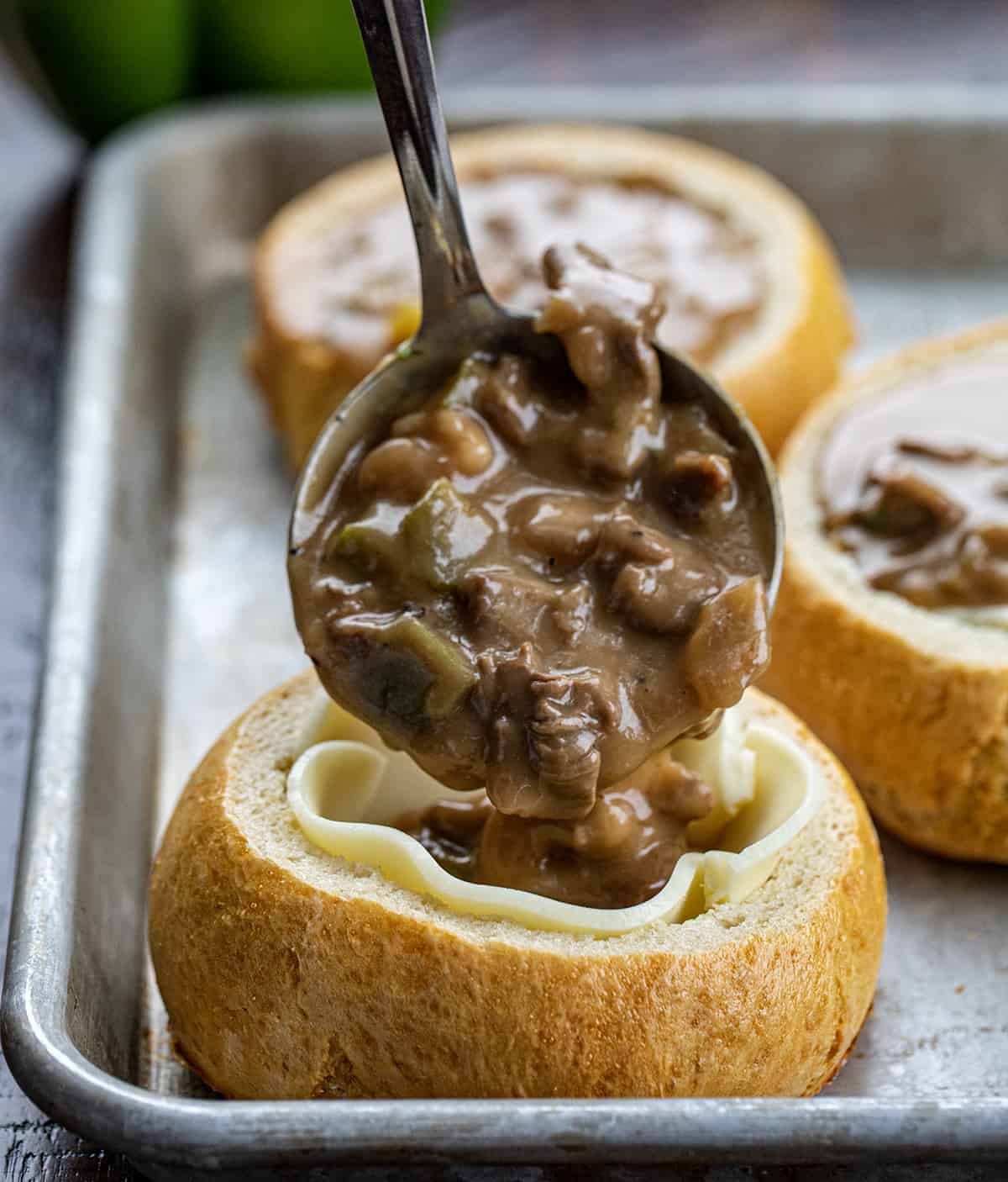 Spooning Philly Cheesesteak Stew into a Breadbowl Lined with Cheese