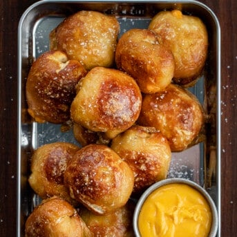 Pan of Cheese Stuffed Pretzel Bombs from Overhead with Side of Cheese.
