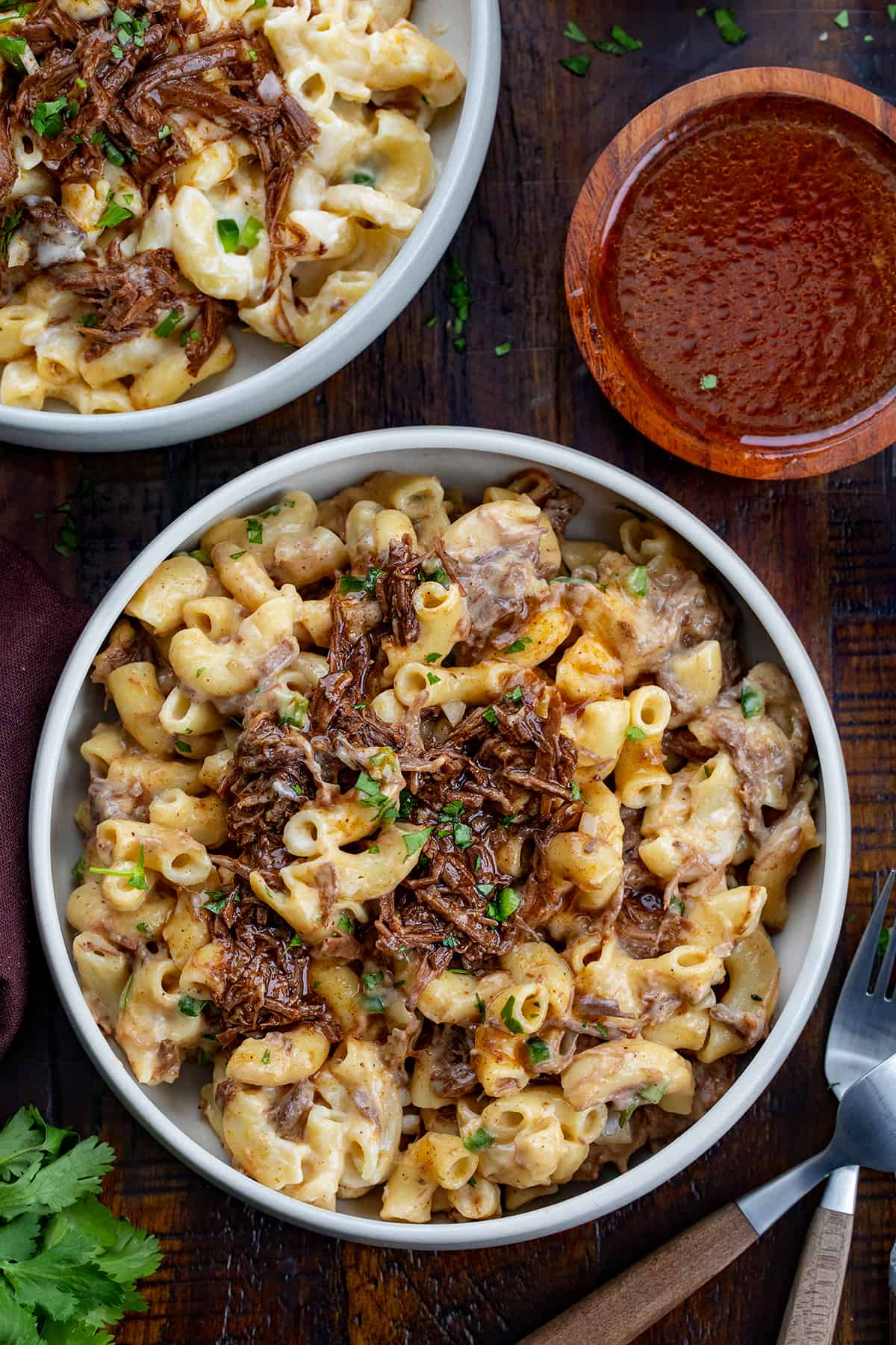 Bowls of Shredded Beef Macaroni and Cheese on a Cutting Board with Sauce.