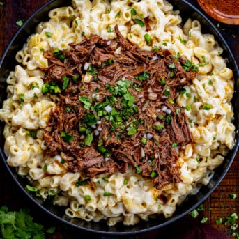 Skillet of Shredded Beef Macaroni and Cheese on a Cutting Board.