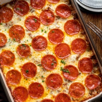 Overhead of a Spaghetti Pizza Casserole on a Cutting Board with Plates and Forks.