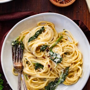 Plates of Asiago Pasta with Forks on a Cutting Board.