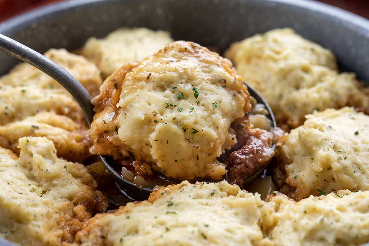 Spoon Picking up a Dumpling from a pot of Beef Stew with Dumplings.