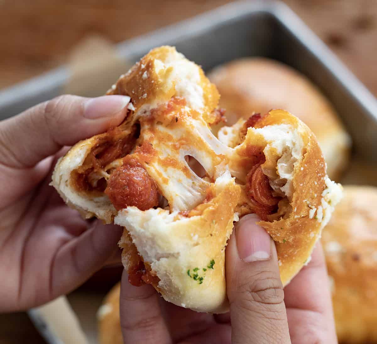 Hands Pulling Apart a Pizza Bomb Showing the Melted Cheese Inside.