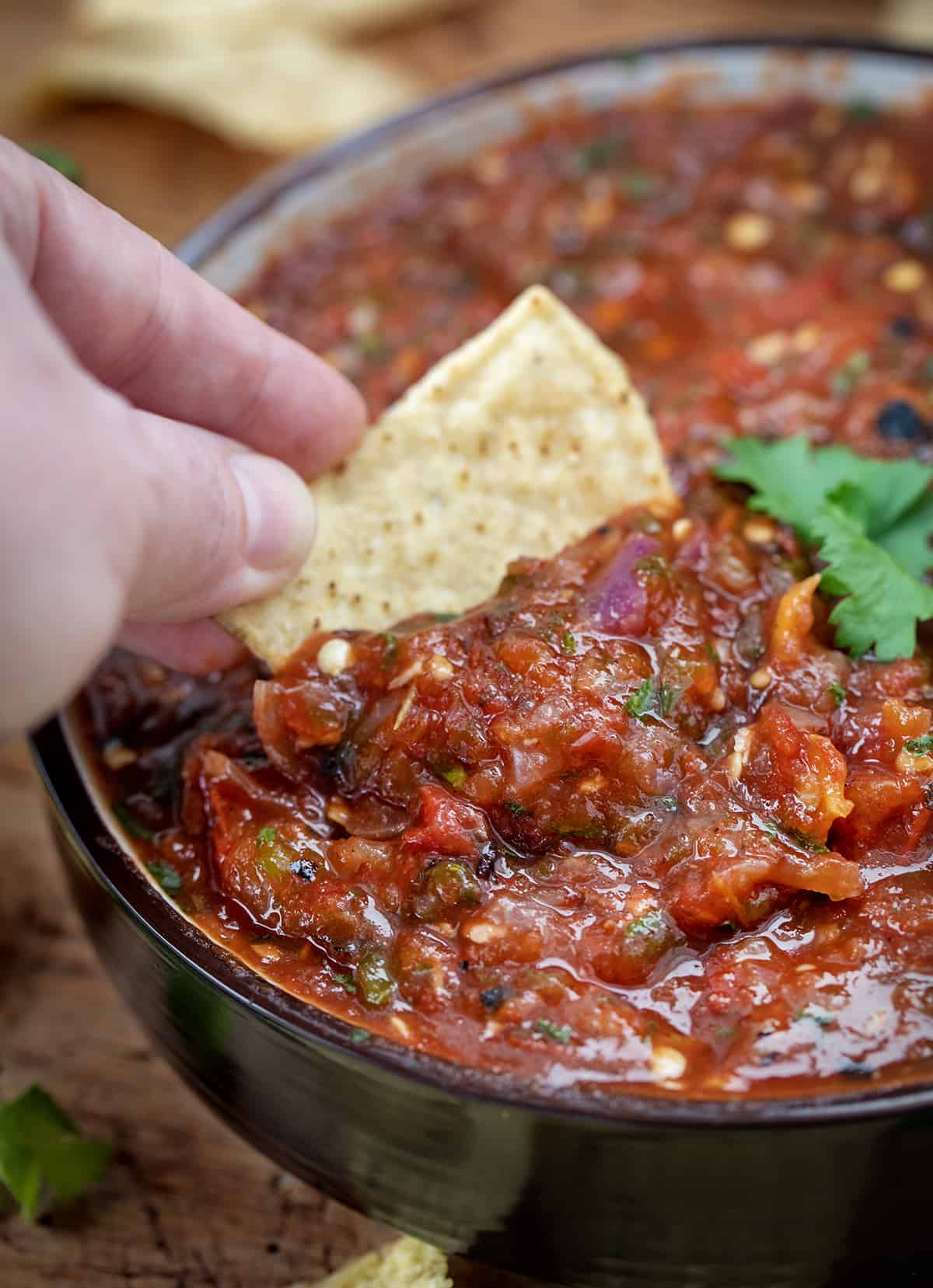 Hand Dipping Chip into Roasted Salsa.