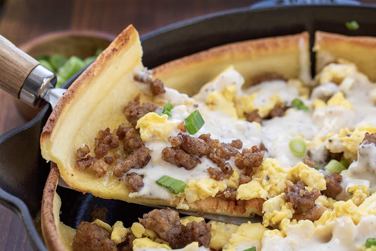 Removing a Slice of Savory Sausage Dutch Baby from Skillet.