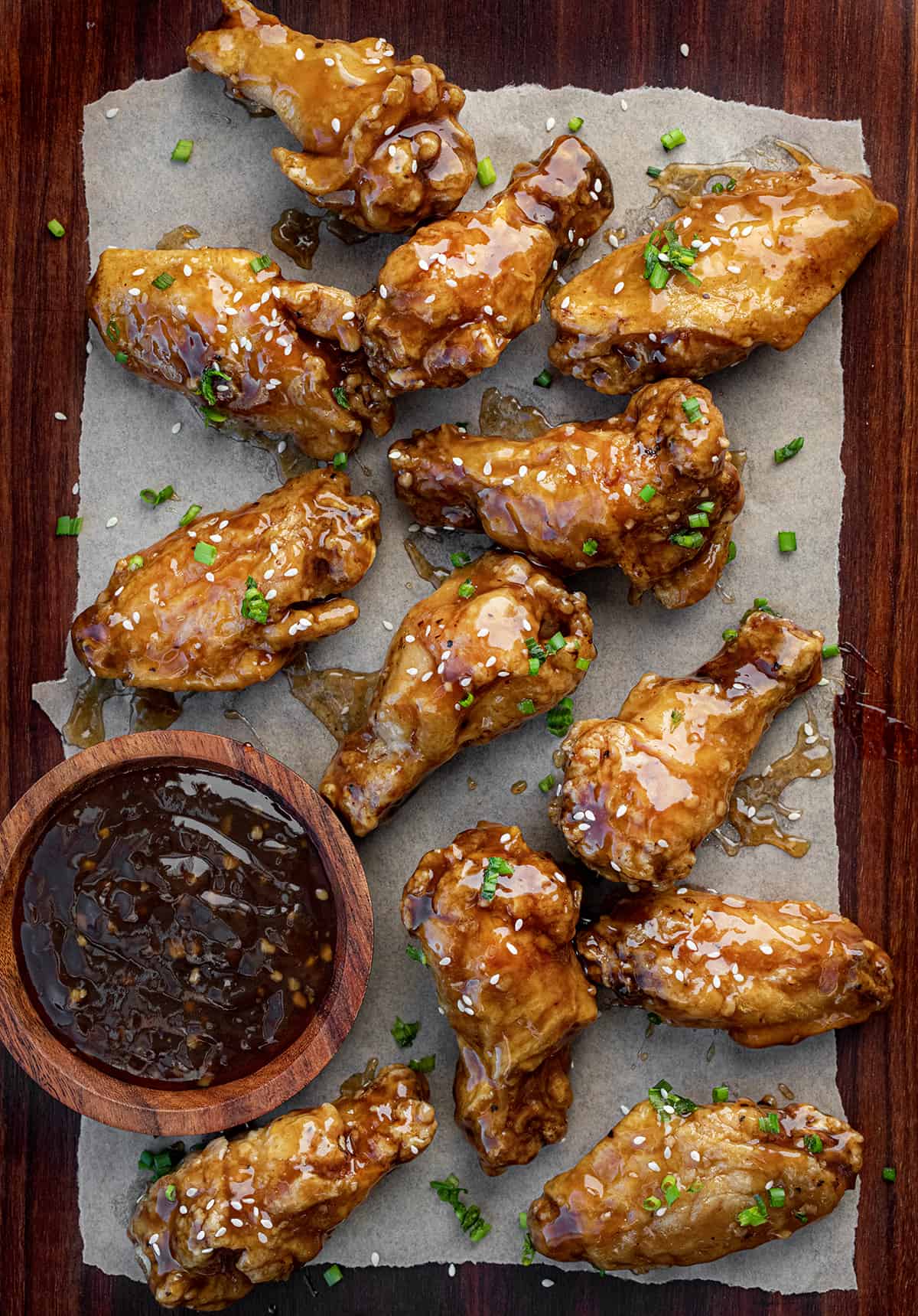 Overhead image of Teriyaki Chicken Wings Next to Sauce and Covered in Sesame Seeds.