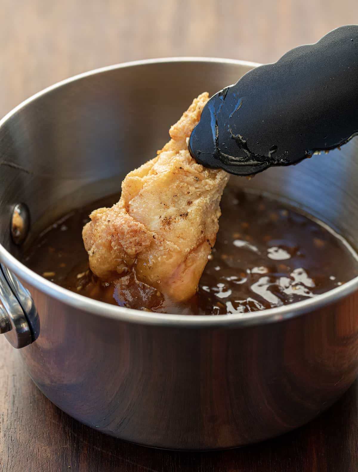 Dipping Fried Chicken Wing into Teriyaki Sauce in a Pan.